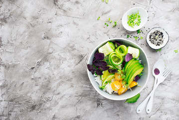 Vegetables rice bowl salad. Avocados, cucumbers, cherry tomatoes, rice, herbs, sesame for spring snack. Top view. On a light background.
