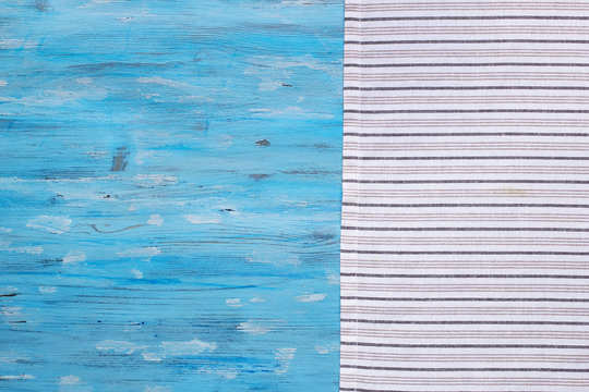 Striped napkin from right side of blue painted old board, abstract food background