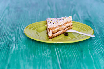 Biscuit cake on a wooden background photographed on a ceramic plate in green.