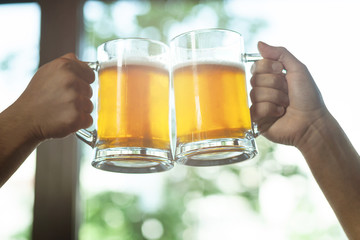 men clicking two glasses with of beer