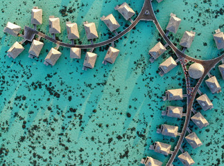 Aerial view of overwater bungalows with thatched roofs in the Moorea lagoon in French Polynesia