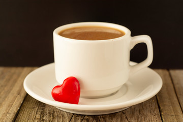 Coffee cup and red Heart on wooden background. Valentine's Day breakfast.