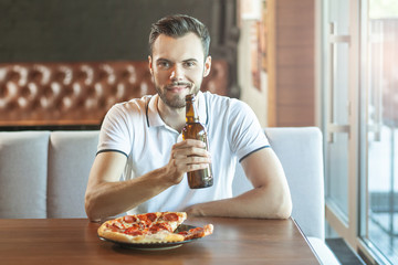 man drinking beer with pizza