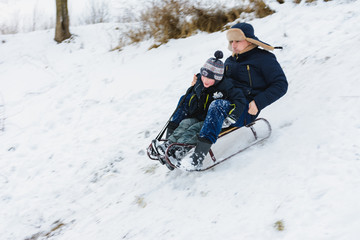 Fototapeta na wymiar Dad and son ride in sledding, baby is fun