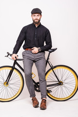 Young bearded hipster man leaning on fixie bicycle over white background