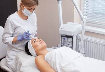 The doctor-cosmetologist makes the procedure treatment of Couperose of the facial skin of a...