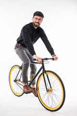 Fototapeta na wymiar Portrait of a hipster beard man riding on bicycle over gray background