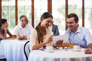 Couple discussing on digital tablet at table