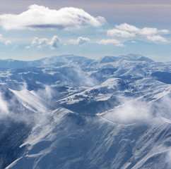 Fototapeta na wymiar Snowy sunlight mountains in haze and cloudy sky