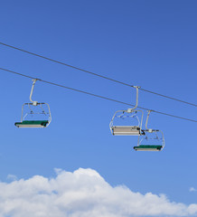 Sunlight chair-lift and blue sky with clouds at ski resort