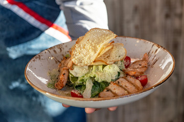 Waiter Holding A Plate wih Caesar Salad with Chicken Fillet