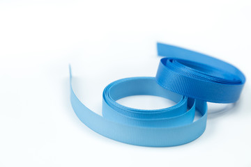 Two silk ribbons of a blue and blue shade for finishing and handwork lie on a white background....