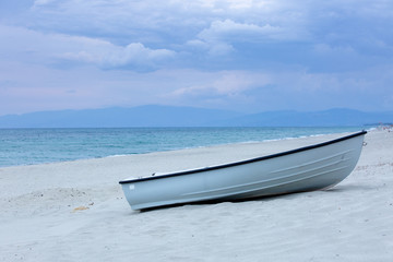 One ship on the beach under clouds . Evening light.