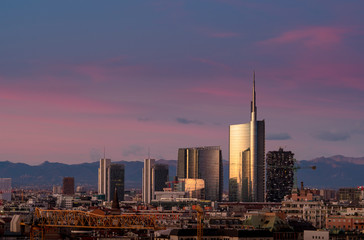Fototapeta na wymiar Milan skyline at sunset with modern skyscrapers in Porta Nuova business district in Italy. Panoramic view of Milano city. The mountain range of the Lombardy Alps in the background.