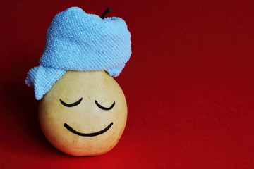 Spa salon. Relaxed happy yellow pear with blue towel on red background. Art idea.