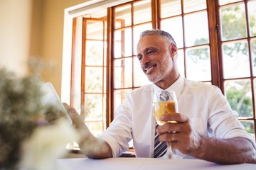 Businessman using mobile phone while having white wine