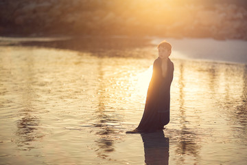 Fototapeta premium boy wrapped in big towel standing on the beach