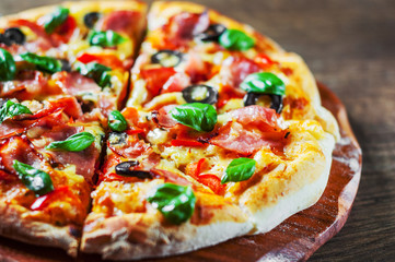 Pizza with Mozzarella cheese, ham, pepper, olive, meat, Tomato sauce, Spices and Fresh Basil. Italian pizza on wooden background