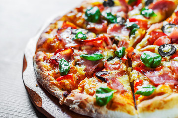 Pizza with Mozzarella cheese, ham, pepper, olive, meat, Tomato sauce, Spices and Fresh Basil. Italian pizza on wooden background