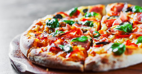 Pizza with Mozzarella cheese, ham, pepper, olive, meat, Tomato sauce, Spices and Fresh Basil. Italian pizza on wooden background