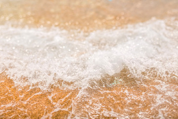 Sea wave rolling on the shore. Coral yellow sand. White water spray.