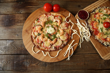 two seafood pizzas with shrimps and mozzarella cheese on a wooden plate on a wooden rustic table. Mediterranean food. Vegetarian. Flat lay. Top view. With copy space for text.