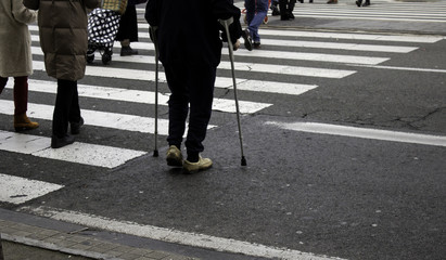 Obraz premium Man with crutches crossing zebra