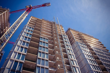 High-rise building under construction. The site with cranes against blue sky