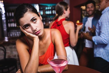 Upset woman sitting at table in nightclub