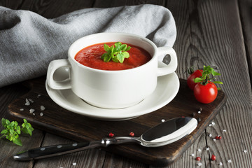 Tomato soup in a white plate on a wooden table
