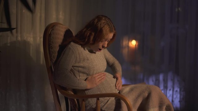 Pregnant woman with long hair first time felt the move of her baby inside. Lady is happy and excited