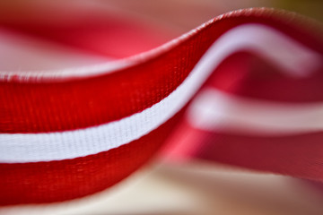 Latvia's flag ribbon on white blur background. Selective focus - obrazy, fototapety, plakaty