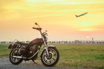 Fototapeta na wymiar Vintage motorcycle with blurry plane at sunset.