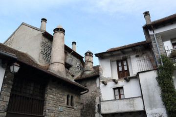 Traditional houses with round chimneys in a Pyrenees mountains village with stone houses and dark roofs during winter in Hecho, Aragon region, Spain