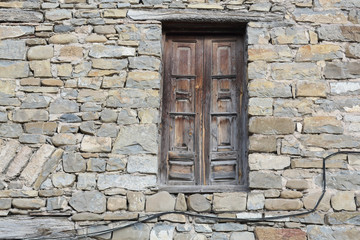 Old wooden door in the void without a balcony on an ancient rural stone made house in the Pyrenees mountains in the traditional Hecho, Aragon, Spain