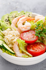 Hawaiian poke bowl with shrimps, rice and vegetables, healthy Buddha bowl with prawns, rice, avocado, cucumber, tomato and lettuce