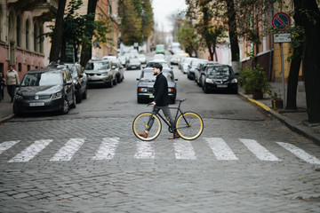 Young hipster man walking across the city street