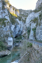 A paved road going into the Veral river canyon, with high grey rock gorge at sunset in Foz de Binies rural area, in Aragon, Spain