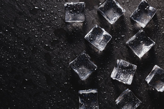 Pieces of ice cubes with water droops on black background. advertising photo