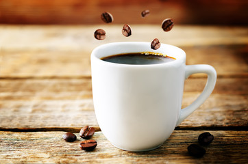 Cup of hot black coffee with coffee beans