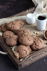 Chocolate cookies with nuts on a brown wooden tray. A old brown concrete background. Copy space for text.