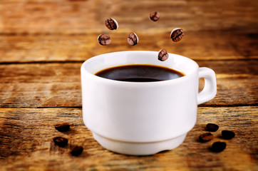 Cup of hot black coffee with coffee beans