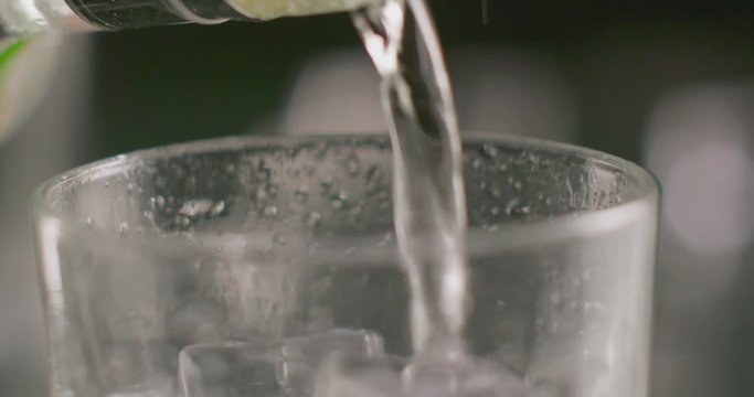 drink being poured into glass with ice