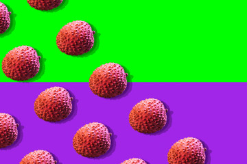 Lychee fruits colorful pattern on a ufo green and proton purple background. Tropical fruits concept. Flat lay. Top view. Space for text.