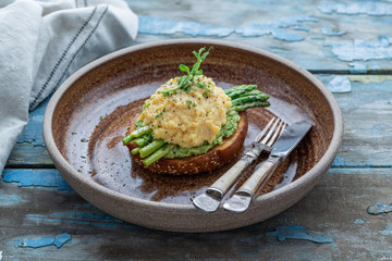 Healthy breakfast with scrambled eggs, avocado and asparagus, close view