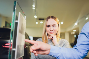 Car salesman helps woman client to choose a new car in the dealership.