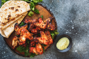 Tandoori chicken wings served with mint chutney dipping sauce. Top view, blank space, rustic background 