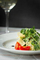vegetarian green salad with croutons and glass wine on dark background, copy space