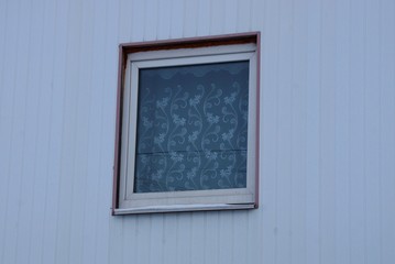 small square window on the gray wall of the building