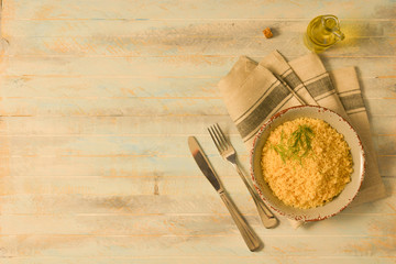 Traditional Couscous with seasoning in grey bowl on grey napkin on wooden table flat lay with copy space 